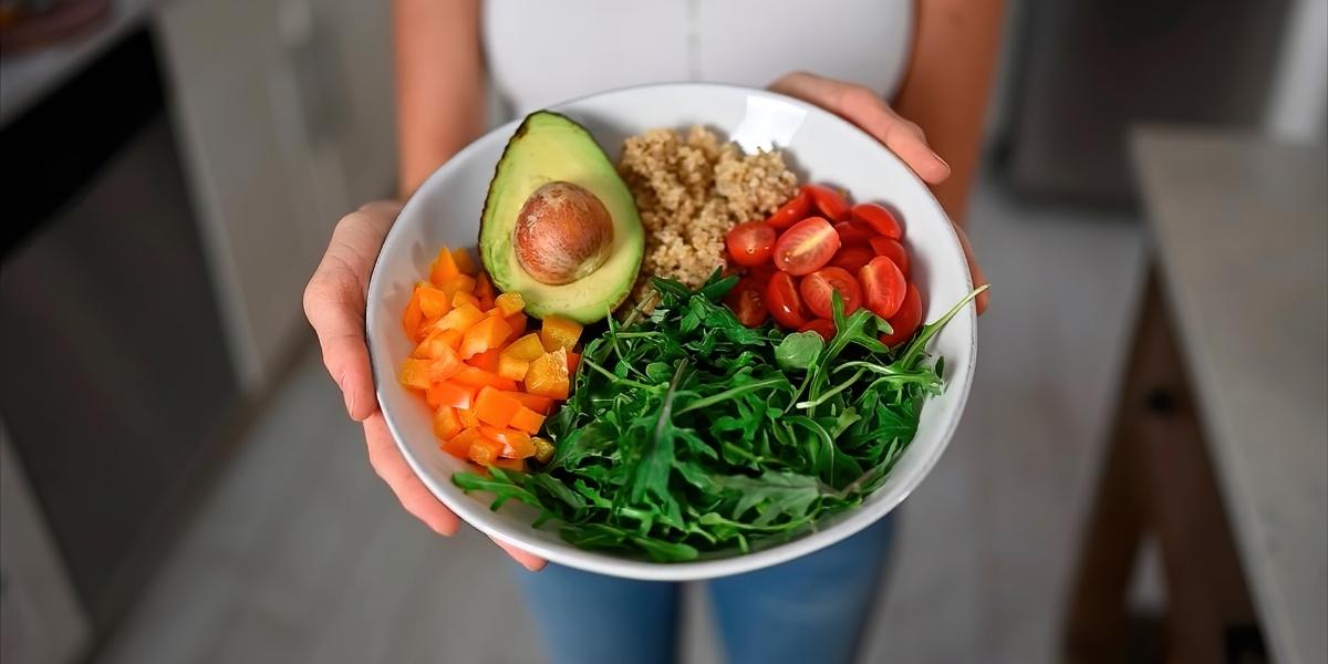 Person offering a colourful vegan salad bowl.