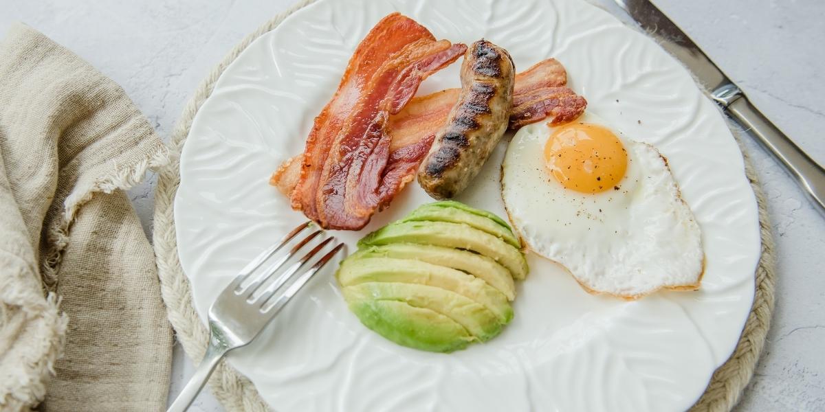 High protein, low-carb breakfast idea; Grilled sausage and bacon, avocado and fried egg.