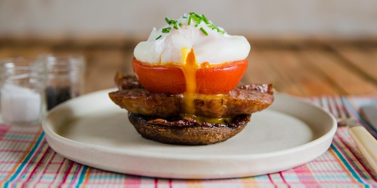 High protein, low-carb breakfast idea; Mushroom breakfast stack with tomato and sausage, topped with a runny poached egg.