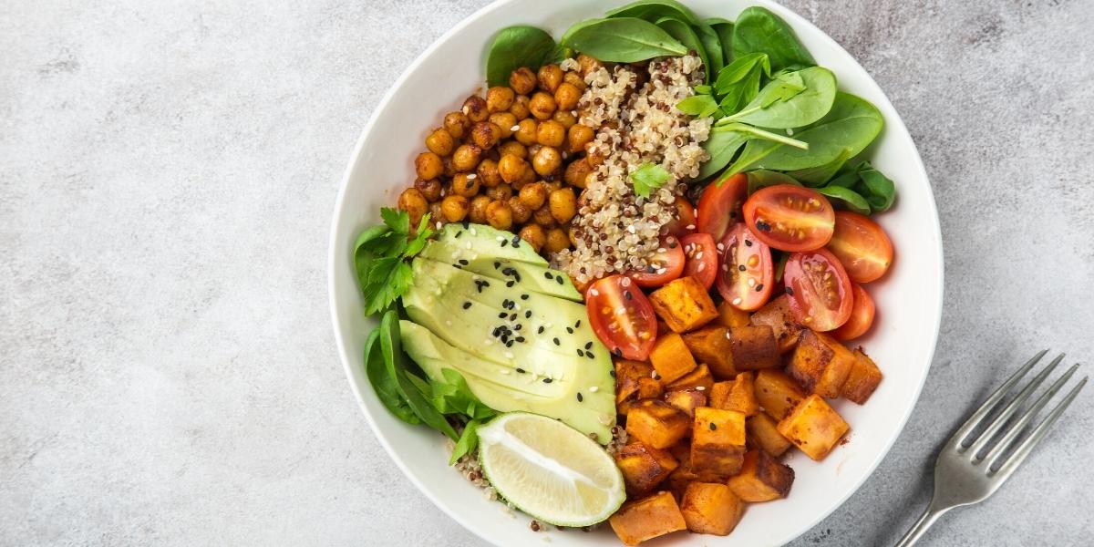 Vegan salad bowl; roasted sweet potato, avocado, tomatoes, fresh baby spinach leaves, quinoa and chickpeas.