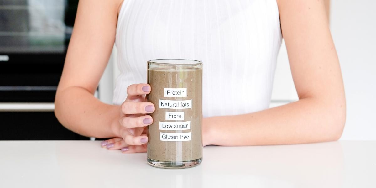 Woman holding glass of Purition Chocolate with nutrient labels