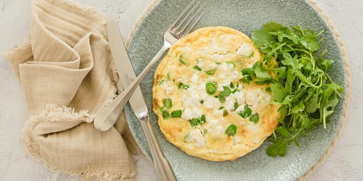 A photograph of a homemade feta cheese and spring onion frittata, with a side of rocket salad.