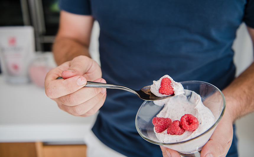 Person eating a serving of Purition that's been stirred into yoghurt and topped with fresh raspberries 