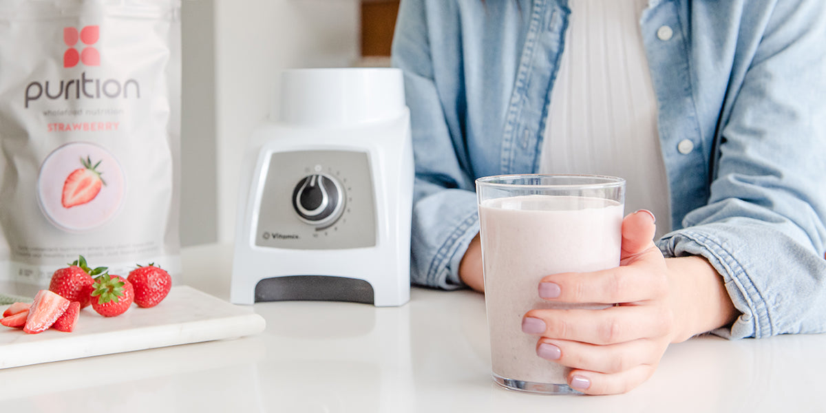 Person holding a Purition strawberry meal shake - high in fibre.