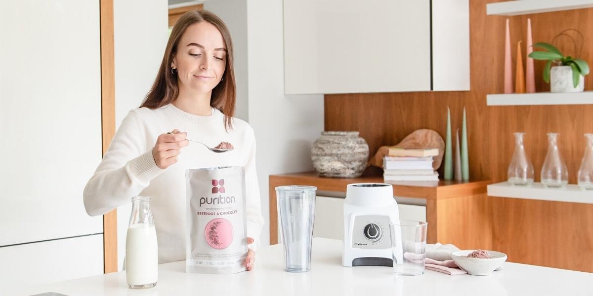 person measuring out a serving of Purition to blend into a shake.