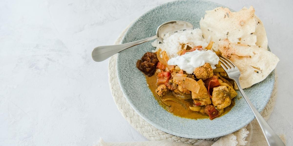 Bowl of healthy chicken and cauliflower curry with poppadom