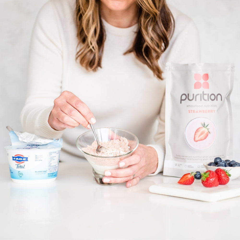 Person stirring a serving of Purition into a glass bowl of yoghurt for a quick & easy meal.