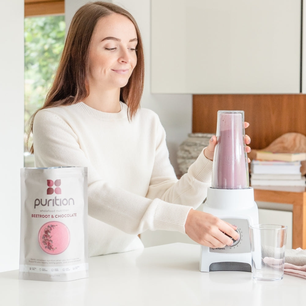 Person in the kitchen blending a Purition shake.