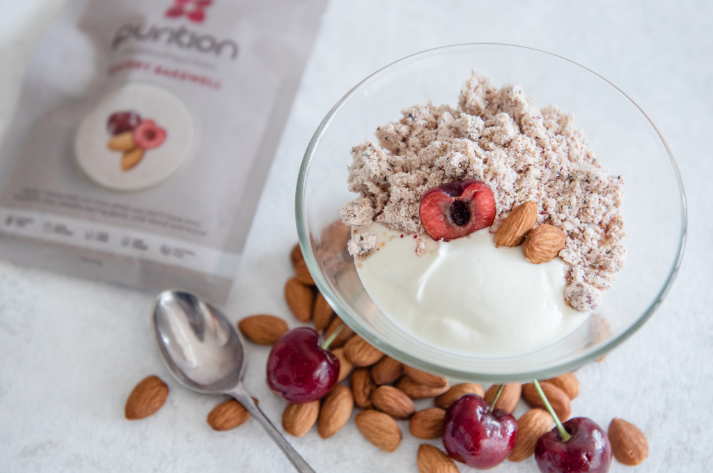 Glass bowl filled with yoghurt, Purition Cherry Bakewell and nuts