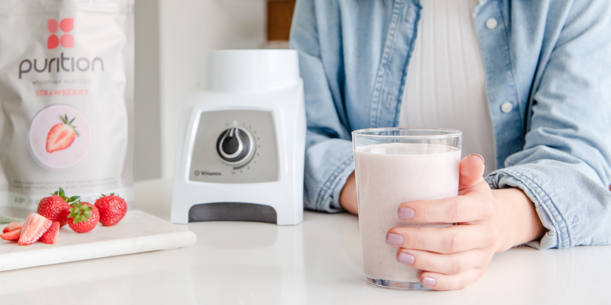 Person holding a Purition Strawberry meal shake.