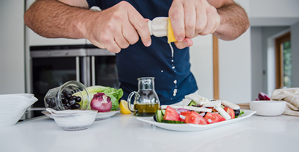 Man squeezing lemon juice over plate of feta salad