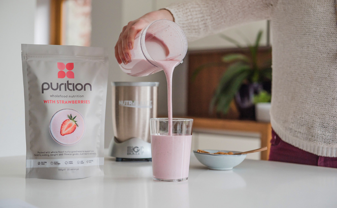 Blended Strawberry Purition meal shake being poured into a glass